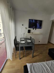 einen Esstisch mit Stühlen und einen TV an der Wand in der Unterkunft Piso junto al Madrid Río in Madrid