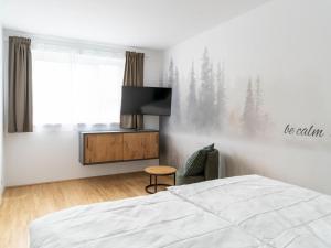 a bedroom with a bed and a tv and a chair at Apartment be calm by Interhome in Mieming