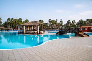 a pool at a resort with a gazebo and blue water at VOI Vila do Farol Resort in Santa Maria