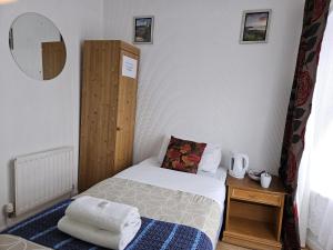 a small bedroom with a bed and a mirror at Rose Marie Guest House in Peterborough