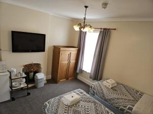 a bedroom with two beds and a flat screen tv at Rose Marie Guest House in Peterborough
