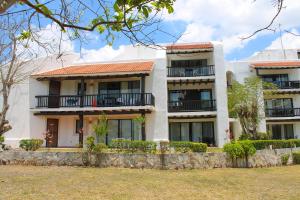 a large white building with balconies and trees at Villas Mayaluum Cozumel in Cozumel