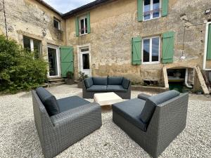a patio with two chairs and couches in front of a building at Le Val Thibaud in Buncey