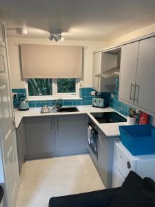 a kitchen with white cabinets and a sink and a window at Claire’s place in Hayle