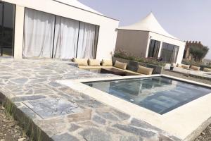 un patio trasero con piscina y una casa en The White Camel en Marrakech