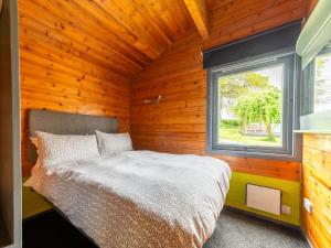 a bedroom with a bed in a wooden wall at Chalet Oak Hot Tub Lodge by Interhome in Launceston