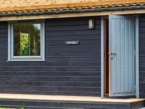a black house with a blue door and a window at Chalet Oak Hot Tub Lodge by Interhome in Launceston +46 photos