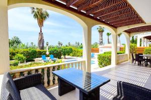 een patio met een tafel en stoelen op een balkon bij Villa Ambrosia in Peyia