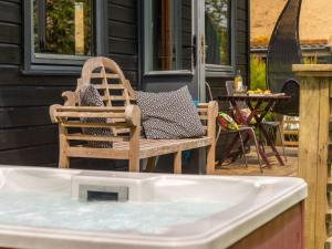 ein Holzstuhl auf einer Terrasse mit einem Whirlpool in der Unterkunft Chalet Chestnut Hot Tub Lodge by Interhome in Launceston