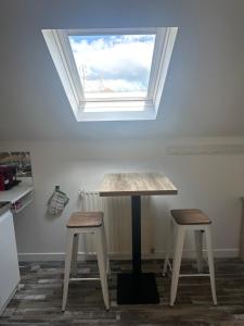 a table and two stools in a room with a window at Appartement Tremblay en France in Tremblay-En-France