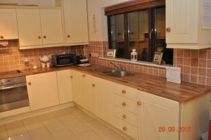 uma cozinha com armários brancos e um lavatório em Woodside Self Catering Lough Rynn em Mohill