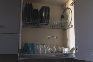 a shelf with glasses and other utensils in a kitchen at WowNavigli Apartment-Sofa Bed Metro M4 Tram 2 in Milan +83 photos