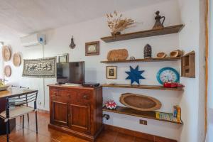 a room with a kitchen with a table and a television at AffittaSardegna-Casa Li Feruli in Trinità dʼAgultu