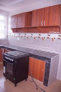 a kitchen with a black stove and wooden cabinets at Maakyere Apartments in Kintampo