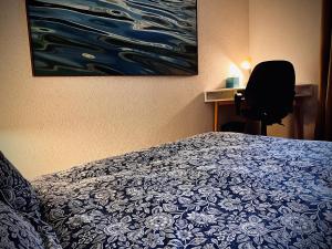 um quarto com uma cama e uma cadeira ao lado de um quadro em La Croisée des Chemins 