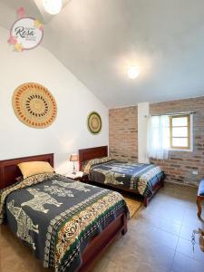a bedroom with two beds and a brick wall at Santa Rosa de Lima Hostal Zuleta in Hacienda Zuleta
