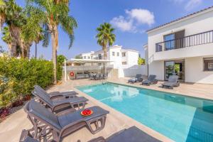 a villa with a swimming pool and palm trees at Villa Christina Coral in Peyia