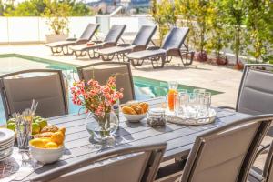 a table with food on it with chairs and a pool at Villa Christina Coral in Peyia