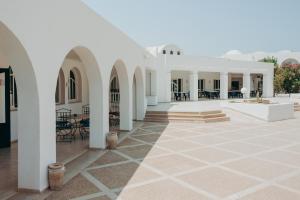Hotel Bougainvillier Djerba في تاجورميس: ساحة مبنى ابيض به طاولات وكراسي
