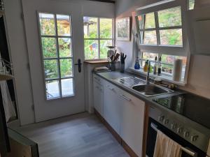 eine Küche mit weißen Schränken und Fenstern sowie einem Waschbecken in der Unterkunft Rechenpeterhäusle in Fischerbach