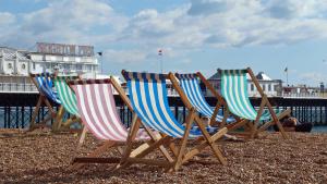 drie stoelen op een strand bij een pier bij Beachfront Getaway 2-Bedroom House with FREE Private Parking & Patio in Brighton & Hove