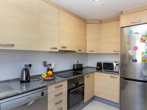 Una cocina con gabinetes de madera y un refrigerador de acero inoxidable. en Apartment Chesa by Interhome, en Benicarló