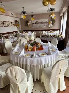 une salle à manger avec des tables et des chaises blanches dans l'établissement Zajazd Skorpion B&B, à Oświęcim