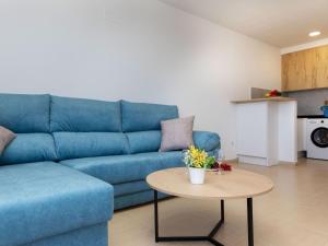 Un sofá azul en una sala de estar con una mesa. en Apartment Barco 3 by Interhome, en Vinarós