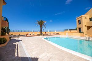 a swimming pool with a palm tree and a building at Complejo Las Tres Palmeras in Valle Gran Rey