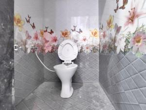 a bathroom with a toilet with flowers on the wall at Family Homestay in Garudeshwar