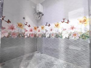 a bathroom with flowers and butterflies on the wall at Family Homestay in Garudeshwar