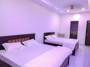 two beds in a room with white walls at Family Homestay in Garudeshwar +3 photos