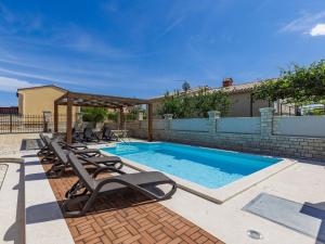 een zwembad met ligstoelen naast een gebouw bij Villa Dzana by Interhome in Mednjan