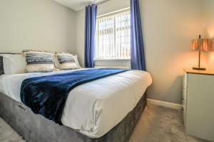 a bedroom with a bed with blue curtains and a window at Host & Stay - Wilshire Way in Milton Keynes +28 photos