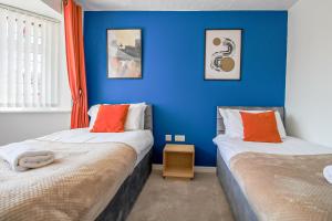 Dos camas en una habitación con paredes azules. en Host & Stay - Wilshire Way, en Milton Keynes
