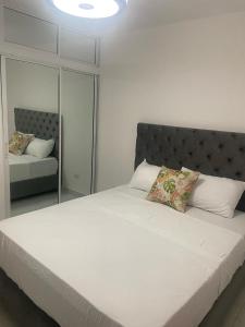 a bedroom with a large white bed with a mirror at Apartamento céntrico en Santiago in Santiago de los Caballeros