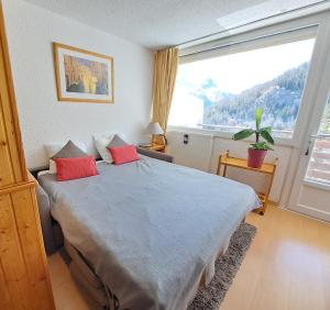 a bedroom with a bed with red pillows and a large window at Location Pra-Loup Vacances in Pra-Loup