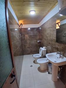 a bathroom with two toilets and a shower and a sink at Bujtina Tusha in Tirana