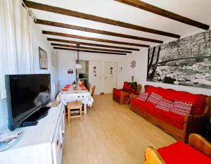 a living room with a tv and a couch and a table at Location Pra-Loup Vacances in Pra-Loup