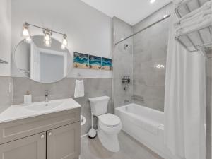 a white bathroom with a sink and a toilet and a tub at Parkside Flat - Seacliff Beach Suites in Leamington