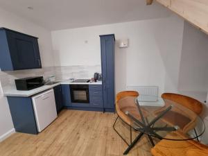 a kitchen with blue cabinets and a table and chairs at Mill View Cottage at Pheasant Lane in Ráistín
