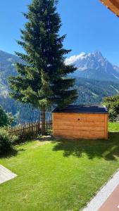 een houten schuur voor een dennenboom bij Hotel Almhof in San Candido