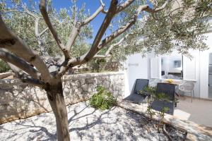 a tree in a yard next to a stone wall at Hotel Stella Mare in Zavala