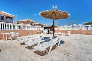 eine Gruppe Stühle und ein Sonnenschirm auf einer Terrasse in der Unterkunft Rincón de sol y relax in Torrevieja