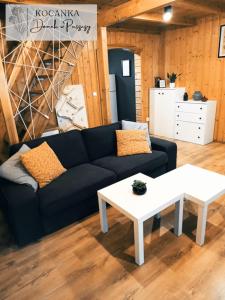 a living room with a black couch and a white table at Domek w Puszczy ,,Kocanka" in Mężyk +21 photos