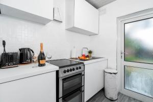 a white kitchen with a stove and a sink at Deluxe Four Bedroom House - Garden - Parking - Sleeps 7 - Netflix - 559T in Birmingham