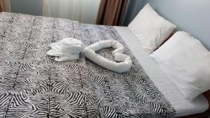 1 cama con edredón blanco y negro y 2 toallas en Hotel Illusions, en Kakamega