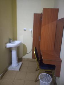 baño con lavabo, escritorio y silla en Hotel Illusions, en Kakamega