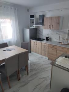 cocina con mesa, nevera y armarios en Sobe kuća za odmor apartmani Auto Klarić, en Nova Gradiška