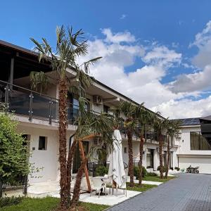 a building with palm trees in front of it at Pensiunea White Department in Vlădeşti